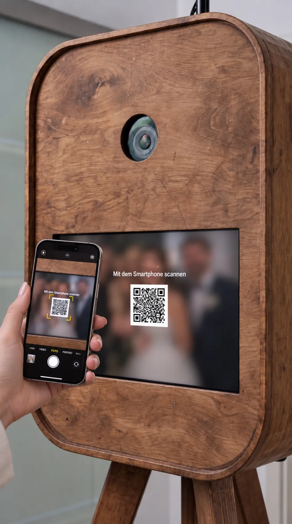 Eine Hand hält ein Smartphone vor das Display der Fotobox und scannt den QR-Code.